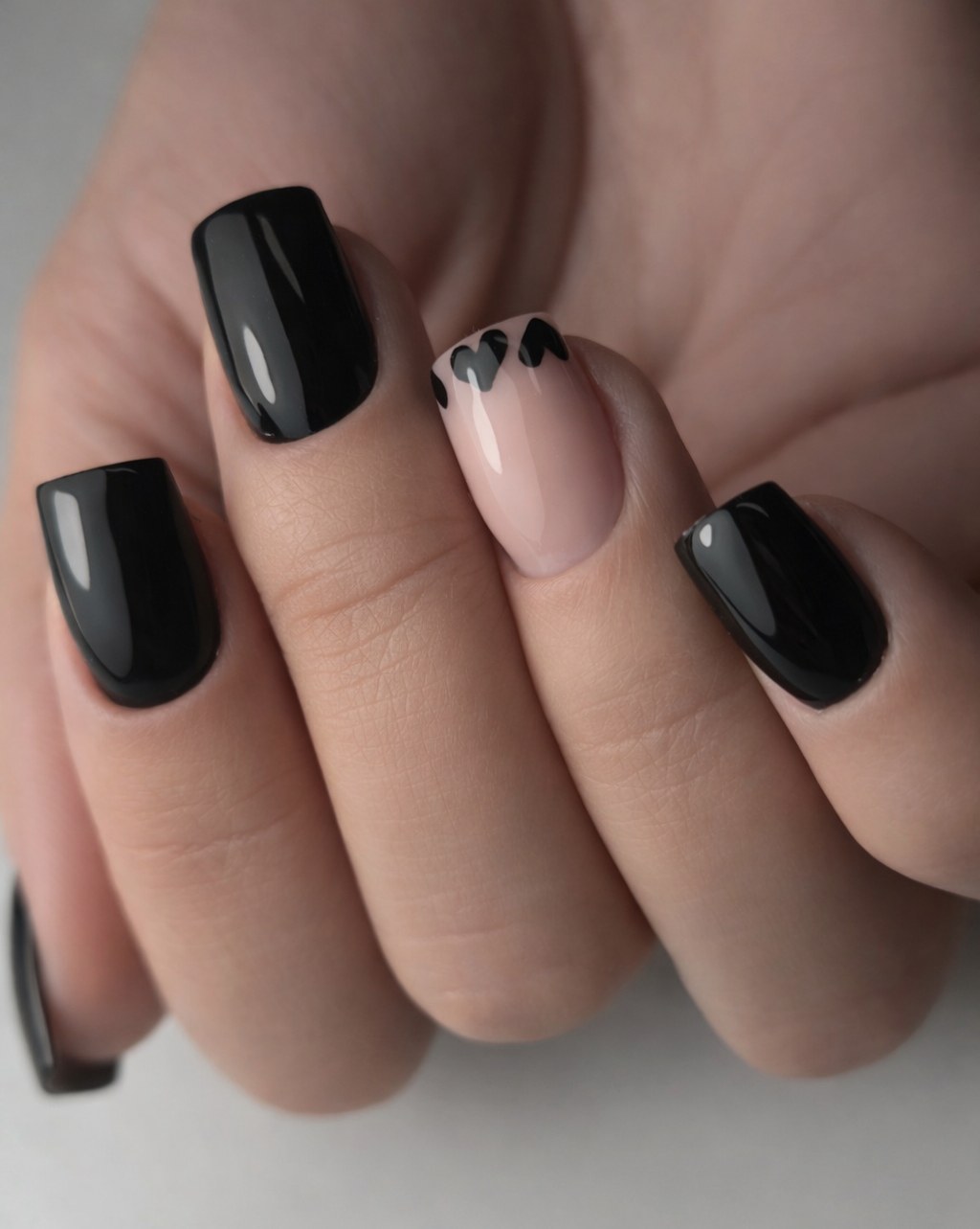 Zwarte vierkante nagels met een nude nagel met hartjes