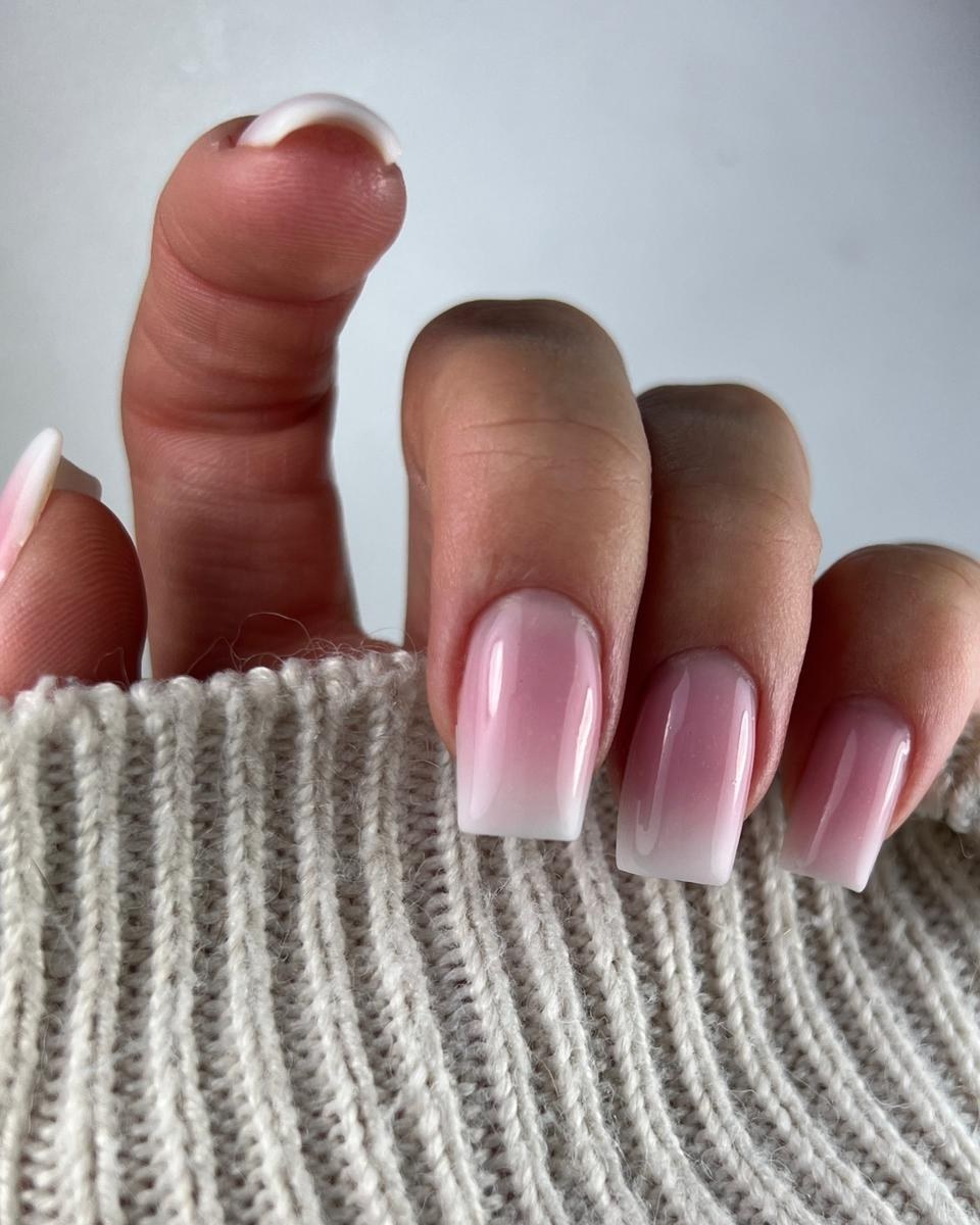 Roze-witte ombré nagels op een gebreide mouw
